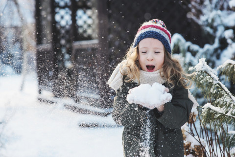 petite fille en tenue d'hiver jouant avec la neige