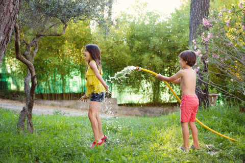 deux enfants jouant avec un tuyau d'arrosage