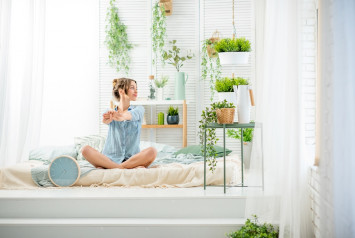 femme assise sur son lit entourée de plantes d'intérieur